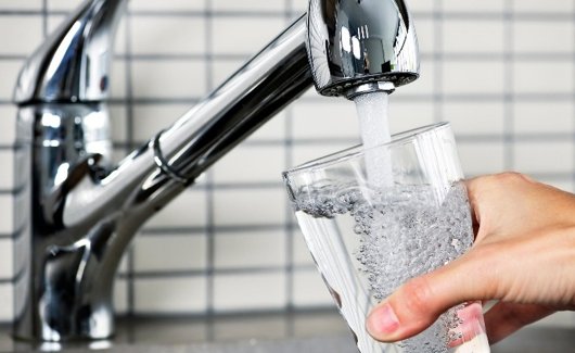 Vatten rinner från en kran ner i ett glas