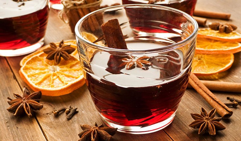 Glas med glögg, kanelstång och stjärnanis på ett träbord